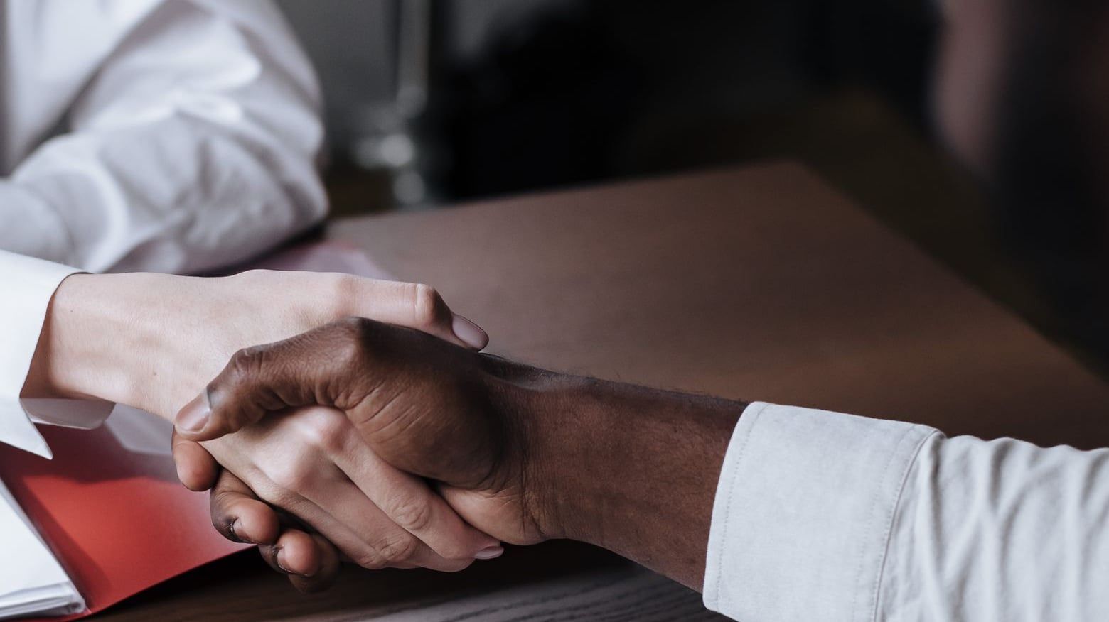Poignée de main entre deux personnes autour d'une table de travail